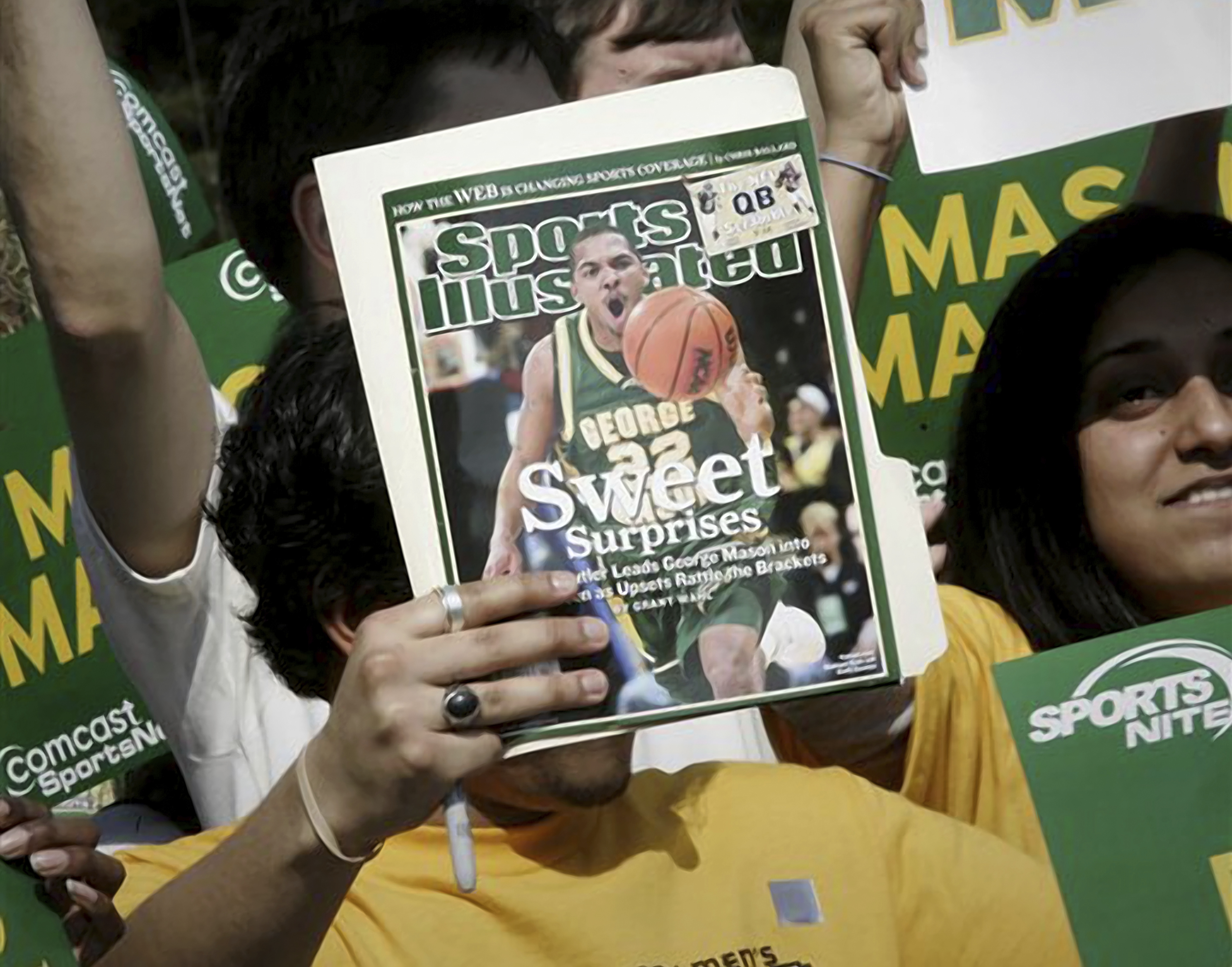 FILE - A George Mason University fan holds up the cover of Sports Illustrated magazine at a send off for the team, Wednesday, March 29, 2006, in Fairfax, Va. The publisher of Sports Illustrated has notified employees it is planning to lay off a significant portion — possibly all — of the outlet's staff after its license to use the iconic brand's name in print and digital was revoked. In an email to employees Friday morning, Jan. 19, 2024, the Arena Group, which operates Sports Illustrated and related properties, said that Authentic Brands Group has revoked its marketing license. (AP Photo/Lawrence Jackson, File)