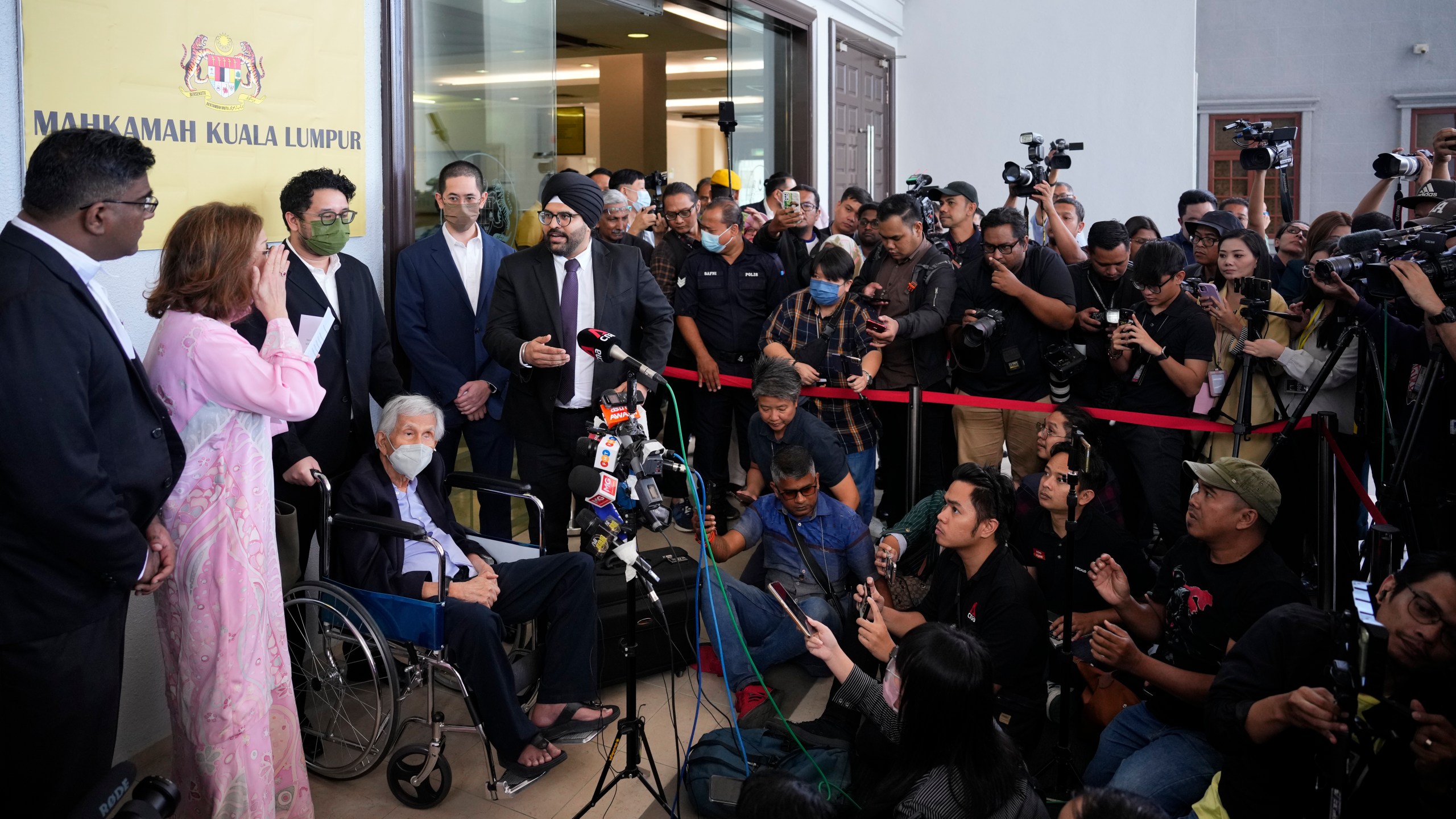 Former Malaysian Finance Minister Daim Zainuddin on wheelchair speaks to media at the courthouse in Kuala Lumpur, Malaysia Monday, Jan. 29, 2024. Daim was charged Monday for failing to declare his assets more than two decades after he left office, in a prosecution he slammed as politically driven. (AP Photo/Vincent Thian)