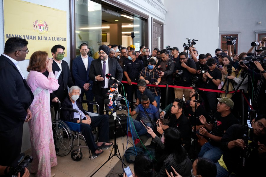 Former Malaysian Finance Minister Daim Zainuddin on wheelchair speaks to media at the courthouse in Kuala Lumpur, Malaysia Monday, Jan. 29, 2024. Daim was charged Monday for failing to declare his assets more than two decades after he left office, in a prosecution he slammed as politically driven. (AP Photo/Vincent Thian)