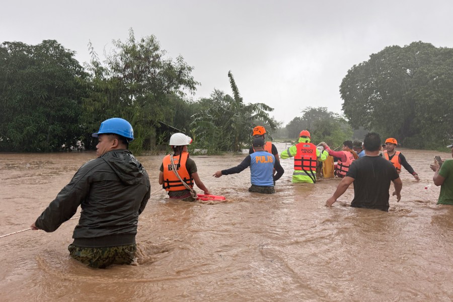 Rescuers help residents as they negotiate floods caused by powerful Typhoon Krathon locally called "Typhoon Julian" at Bacarra, Ilocos Norte province, northern Philippines on Monday, Sept. 30, 2024. (AP Photo/Bernie Dela Cruz)