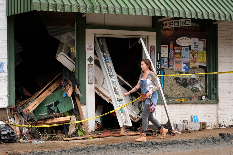 A person walks past a building heavily damaged during Hurricane Helene Tuesday, Oct. 1, 2024, in Hot Springs, N.C. (AP Photo/Jeff Roberson)