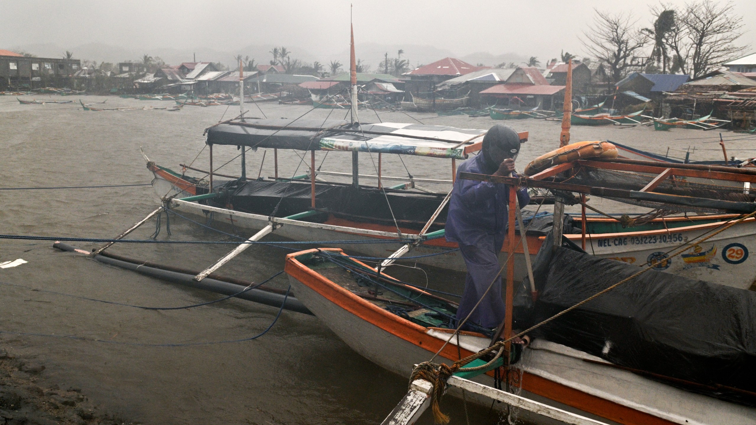 A man tries to secure his boat as rain caused by Typhoon Usagi pours at Santa Ana, Cagayan province, northern Philippines on Thursday, Nov. 14, 2024. (AP Photo/Noel Celis)