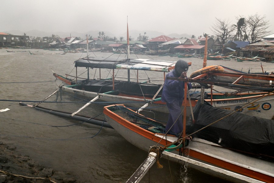 A man tries to secure his boat as rain caused by Typhoon Usagi pours at Santa Ana, Cagayan province, northern Philippines on Thursday, Nov. 14, 2024. (AP Photo/Noel Celis)