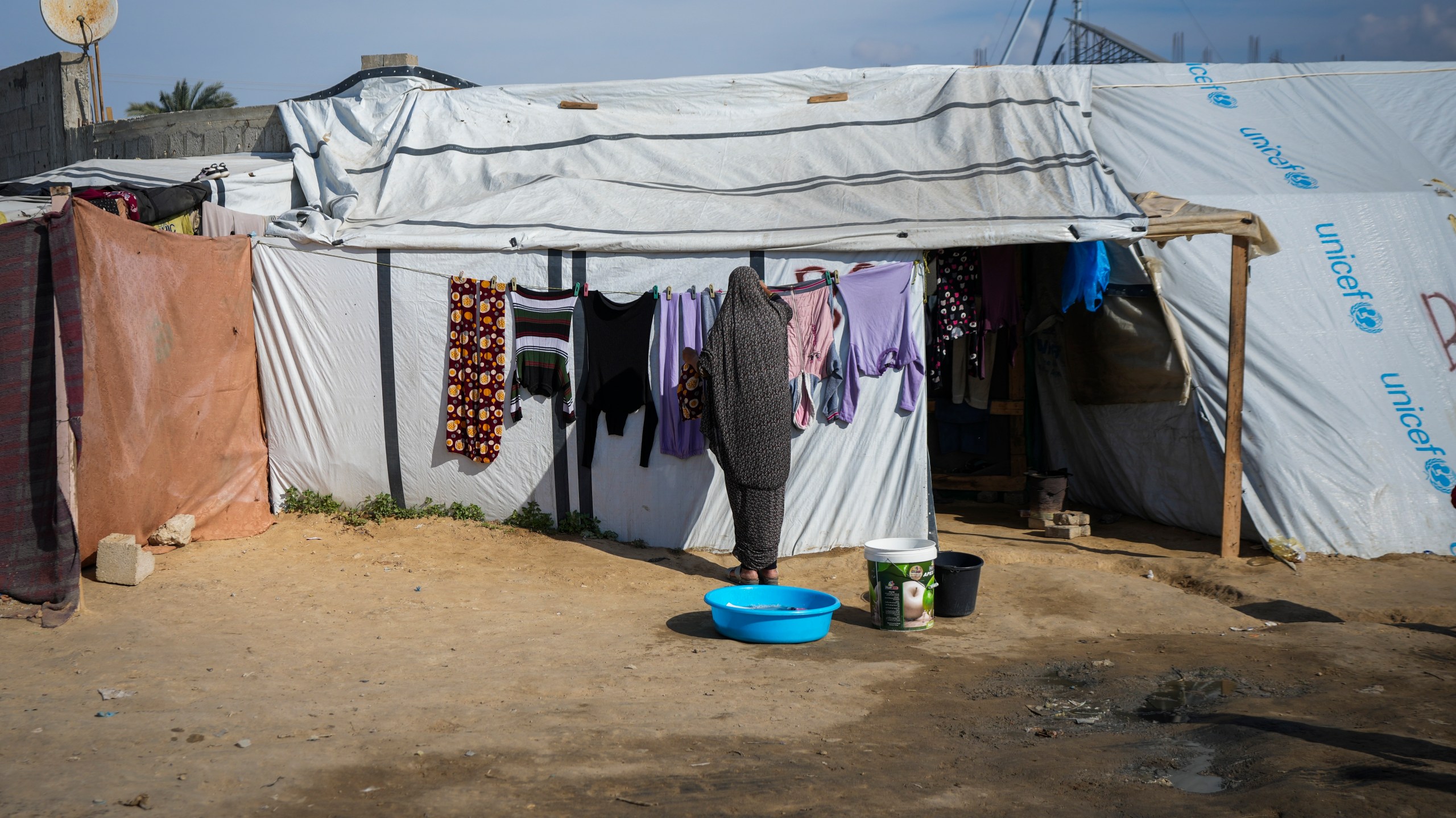 A woman hangs her laundry outside a tent at a camp for displaced Palestinians in Deir al-Balah, central Gaza Strip, Friday Jan. 17, 2025. (AP Photo/Abdel Kareem Hana)