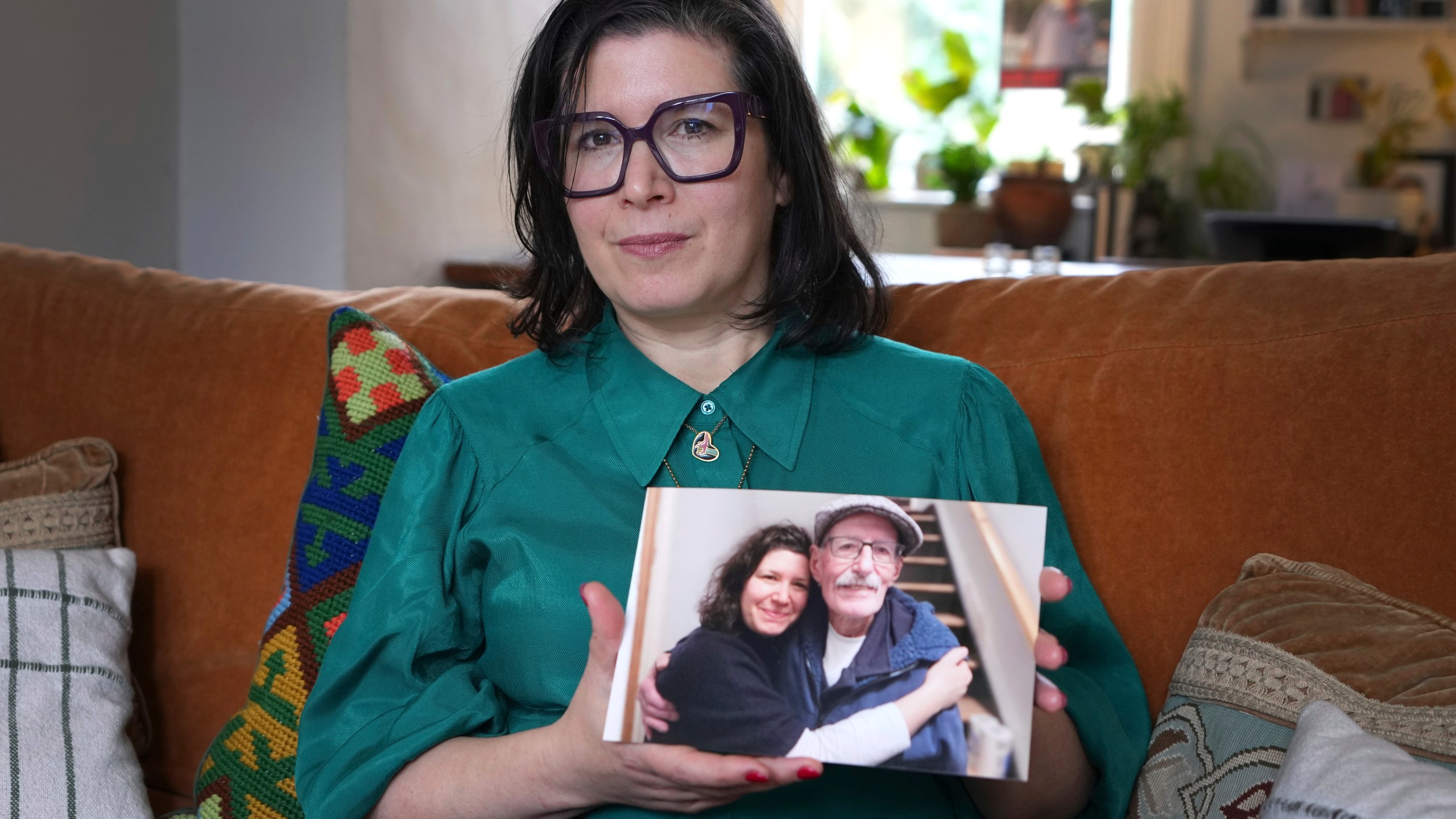 Sharone Lifschitz holds a photograph of herself with her father, Oded Lifshitz, who was abducted by Hamas militants, at her home in London, Friday, Jan. 17, 2025. (AP Photo/Kirsty Wigglesworth)