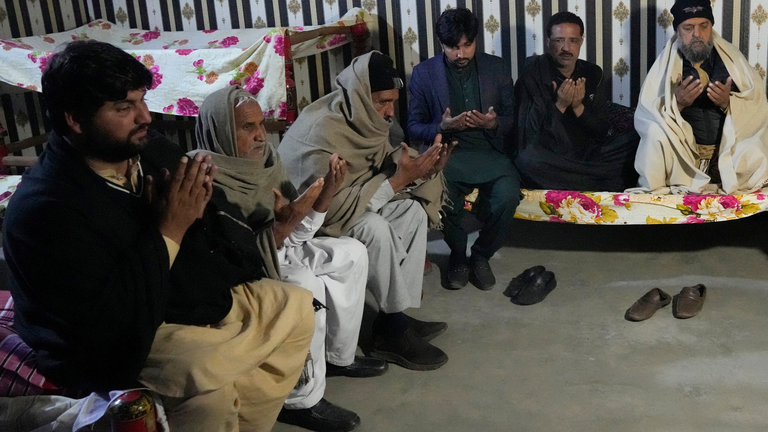 Ahsan Shahzad, father of Suffian Ali, one of the victims of a migrant boat that capsized in West Africa's Atlantic coastline, is consoled by relatives at his home in the village of Dhola, Lalamusa district, Pakistan, Friday, Jan. 17, 2024. (AP Photo/K.M. Chaudary)