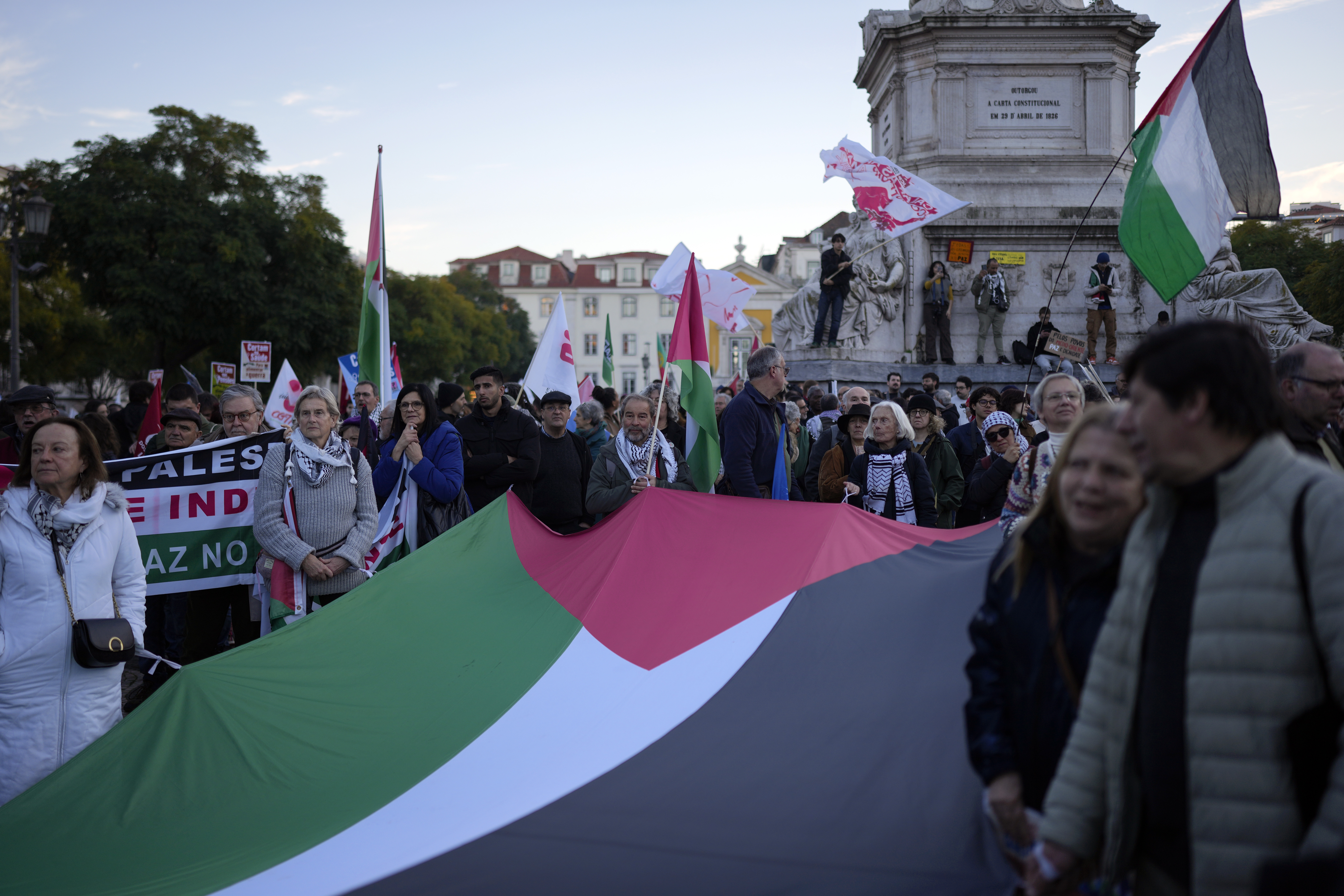 People hold a Palestinian flag during a demonstration for peace and in support for Palestinians, in Lisbon, Saturday, Jan. 18, 2025. (AP Photo/Armando Franca)