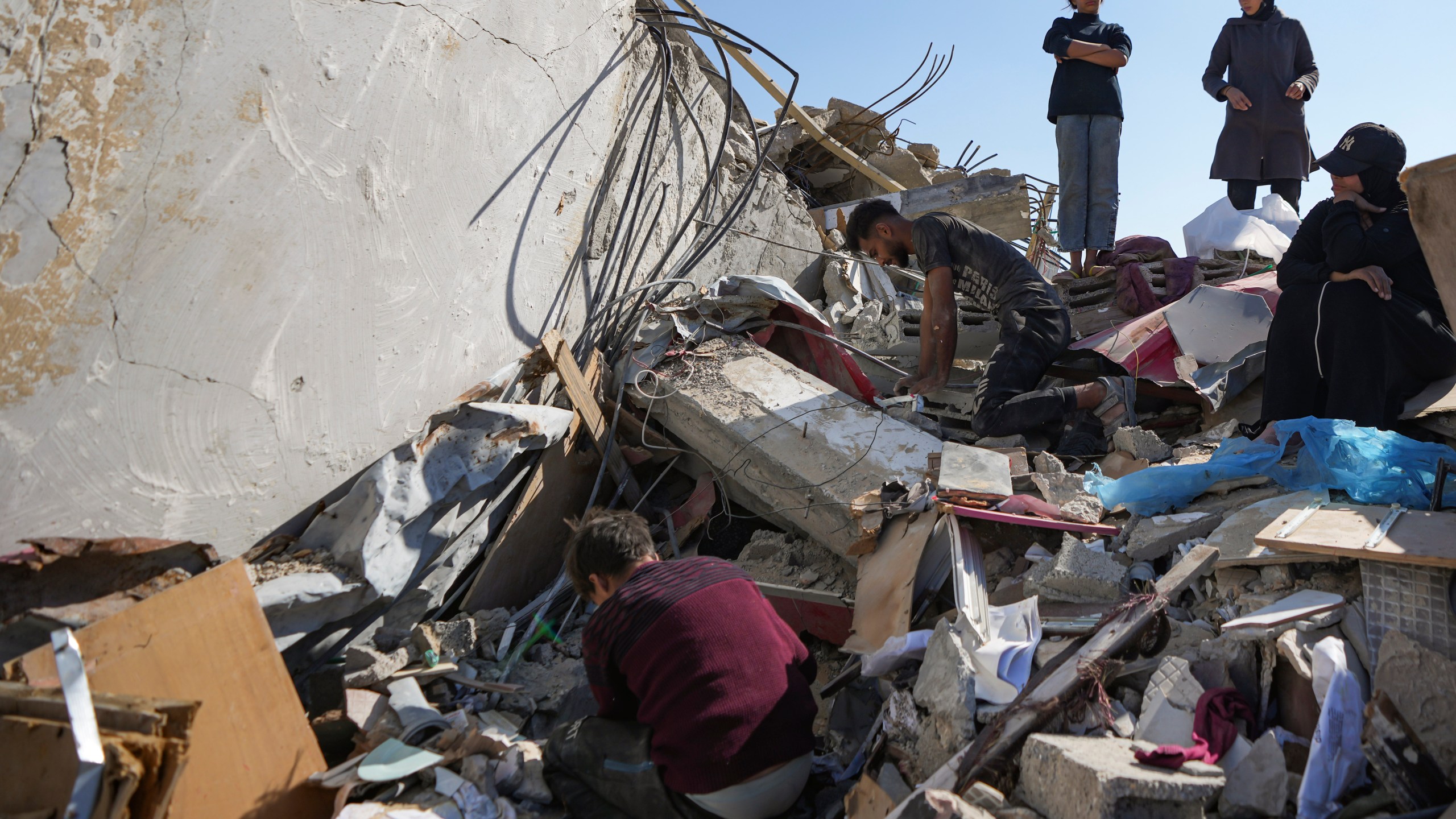 Members of the Abu Al Zamar family salvage items from under the rubble of his destroyed family home, in Rafah, southern Gaza Strip, Tuesday, Jan. 21, 2025, days after the ceasefire deal between Israel and Hamas came into effect. (AP Photo/Abdel Kareem Hana)