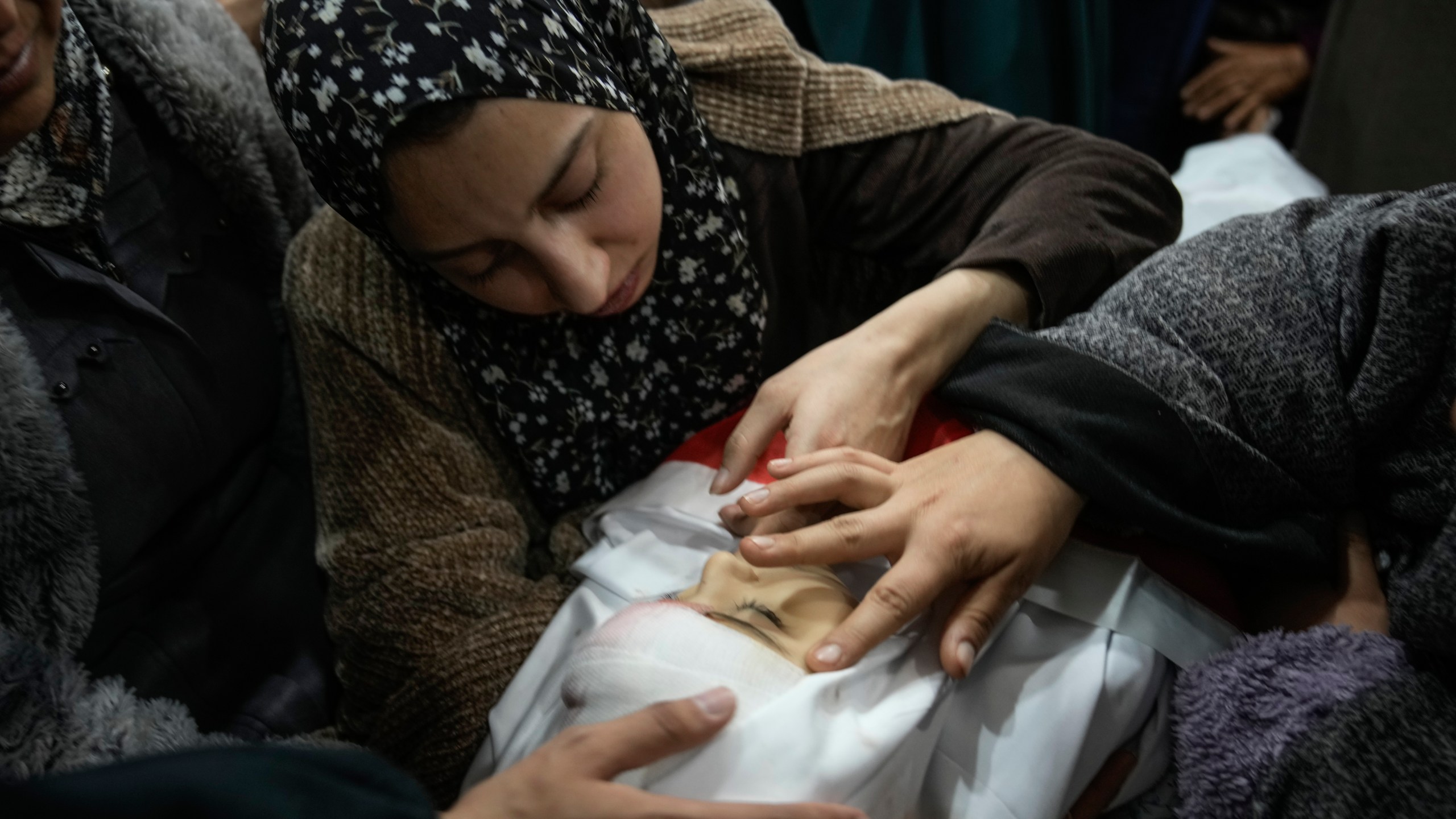 Tima Al-Khatib and another mourner gently caresse the face of her 2-year-old daughter, Laila, during her funeral in the West Bank village of Al-Shuhada, near Jenin, Sunday Jan. 26, 2025. According to the Palestinian health officials she was shot in the head by Israeli forces during an army operation in the area. Israel's military said it was reviewing the incident.(AP Photo/Majdi Mohammed)