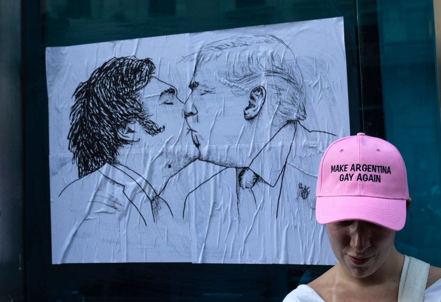 A woman poses for a photo in front of a poster depicting Argentine President Javier Milei and U.S. President Donald Trump sharing a kiss, during a demonstration to protest Milei’s speech at the World Economic Forum in Davos, in which he criticized “sick wokeism,” social welfare, feminism, identity politics and the fight against climate change. (AP Photo/Rodrigo Abd)