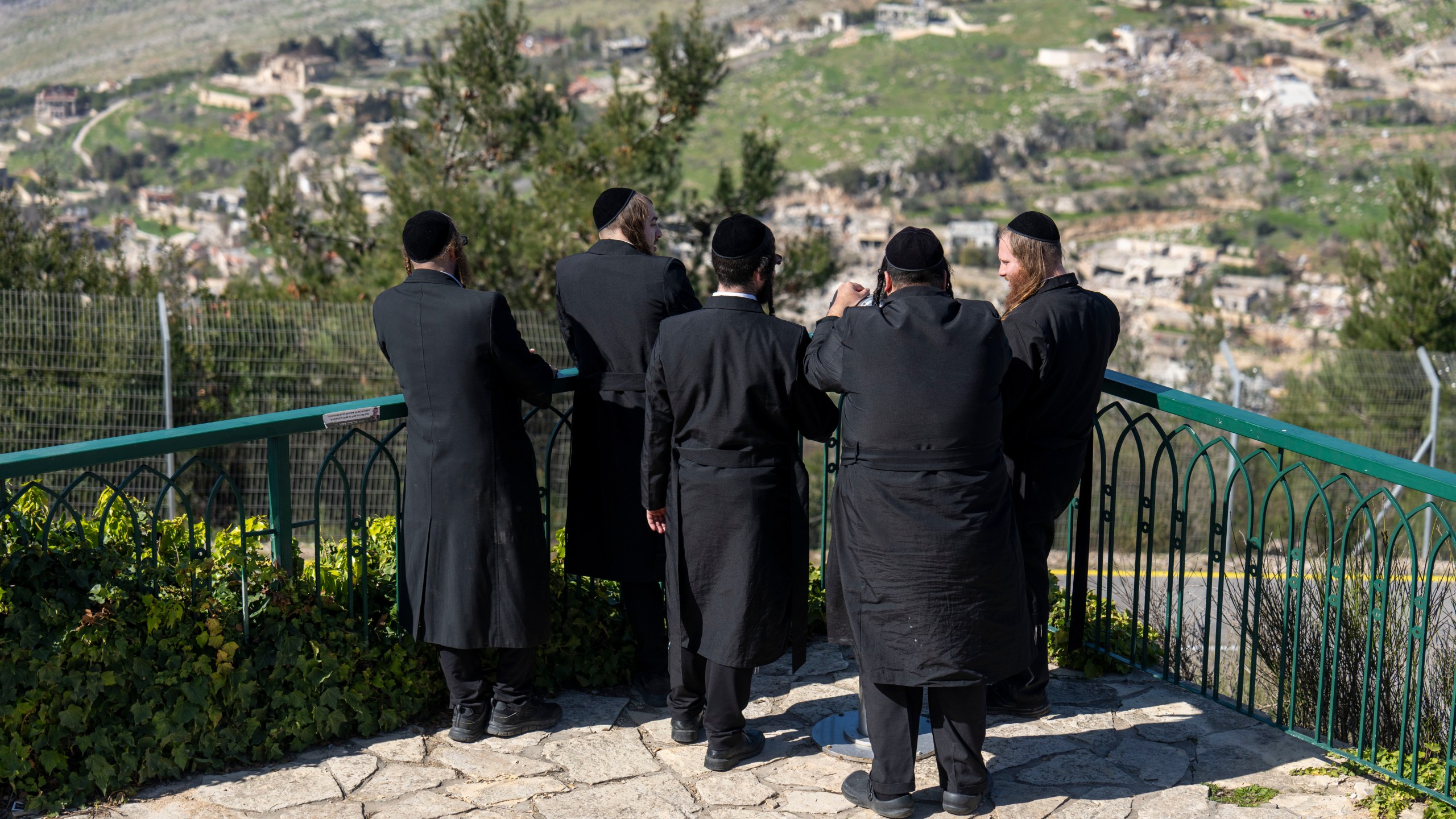 Ultra-Orthodox Jewish men look from Kibbutz Misgav Am in northern Israel at the village of Odaisseh in Southern Lebanon after Israeli forces withdrew from border villages , Tuesday, Feb. 18, 2025. (AP Photo/Ariel Schalit)