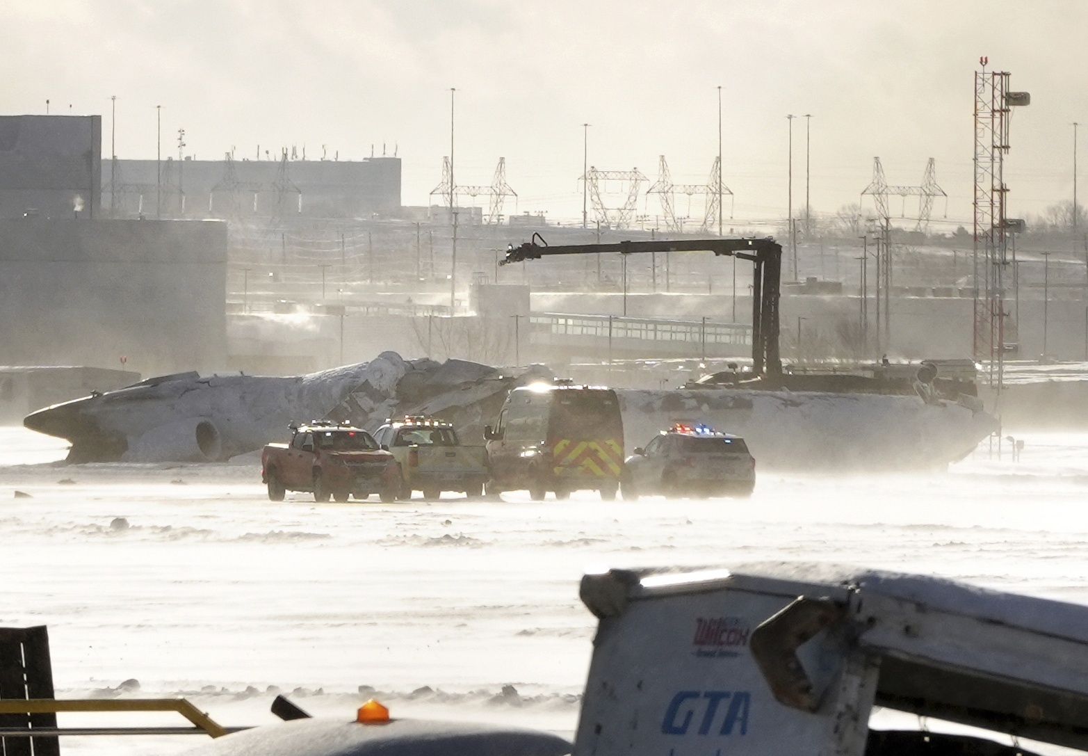 Emergency response vehicles are seen nearby an upside down Delta Air Lines plane, which was heading from Minneapolis to Toronto when it crashed on the runway at Pearson International Airport, in Toronto, Monday, Feb. 17, 2025. (Teresa Barbieri/The Canadian Press via AP)