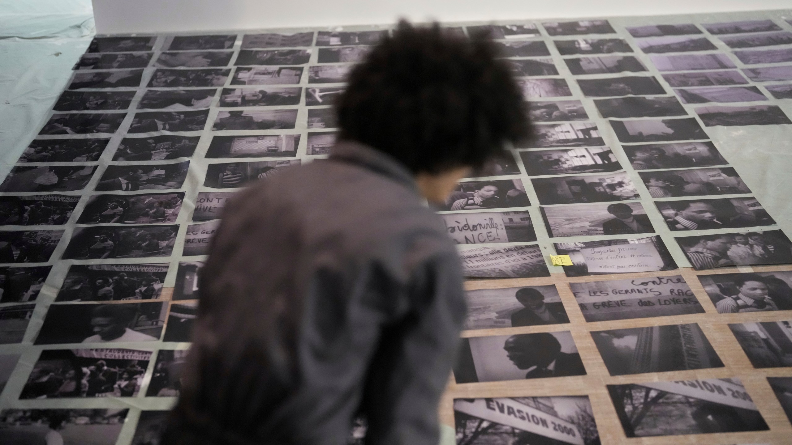 An assistant of French street artist Shuck One places archive images during the preparation of the exhibition "Paris Noir", at the Centre Pompidou Museum, in Paris, Tuesday, Feb. 18, 2025. (AP Photo/Thibault Camus)