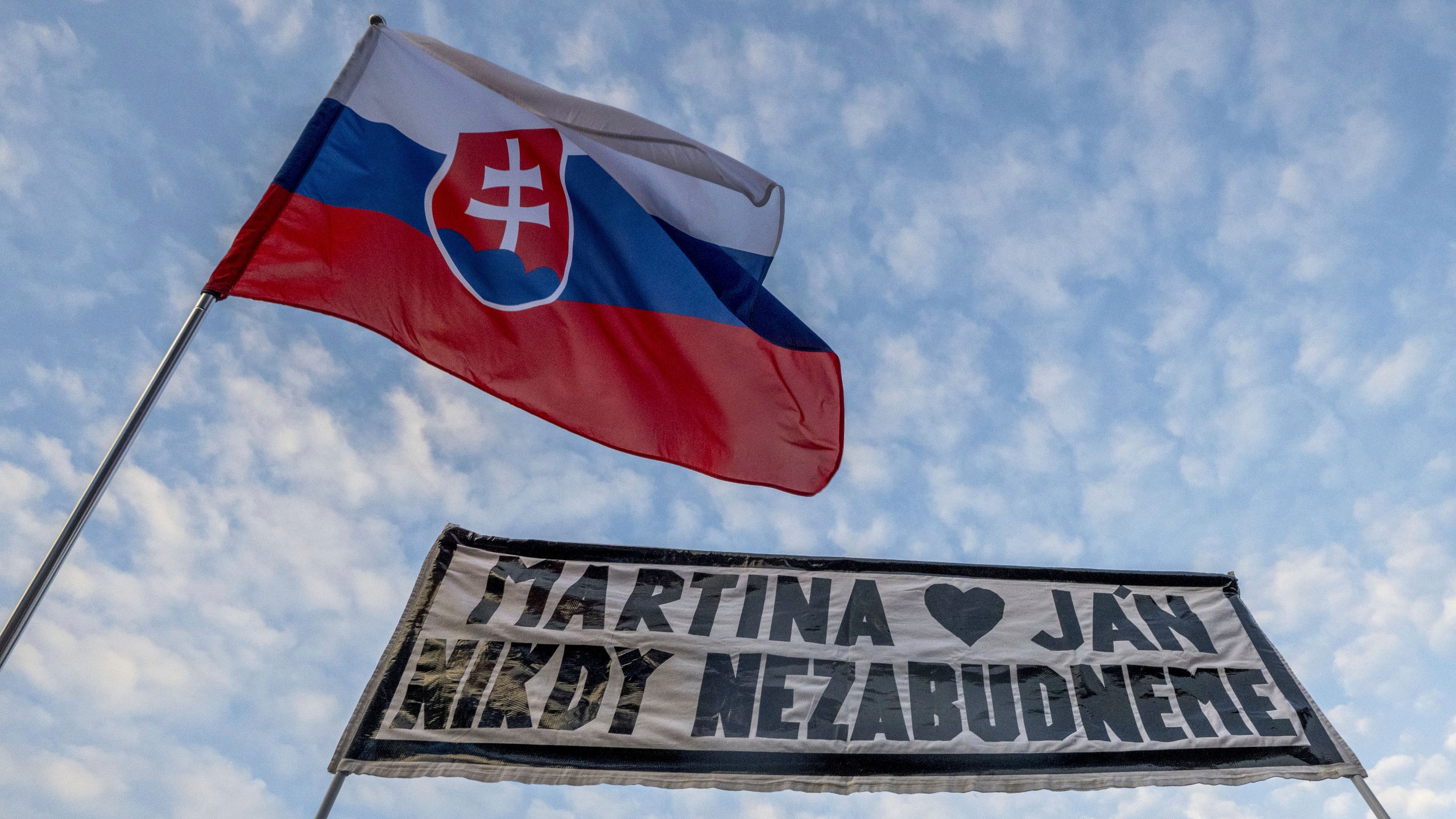 People gather in Bratislava, Slovakia on Friday Feb. 21, 2025, to mark the seventh anniversary of the slayings of an investigative journalist and his fiancee, Jan Kuciak and Martina Kusnirova. Banner reads: "Martina and Jan: We will never forget". (Vaclav Salek/CTK via AP)