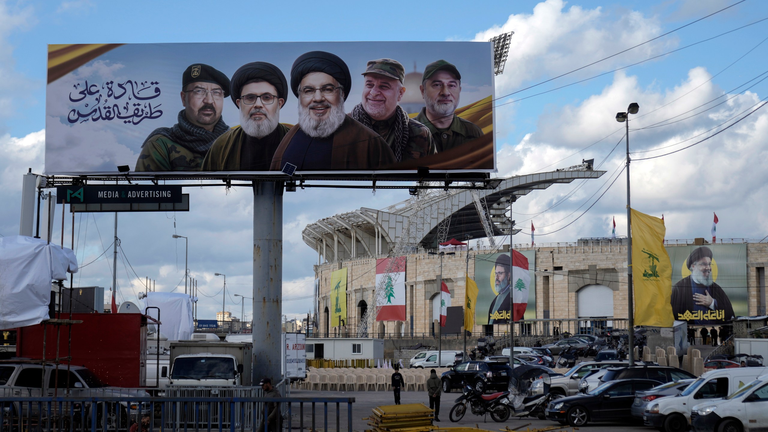 People walk past a billboard with pictures of the late Lebanon's Hezbollah leader Sayyed Hassan Nasrallah, center, late Lebanon's Hezbollah leader Sayyed Hashem Safieddine, second left, Hezbollah top commander Fouad Shukur, left, Hezbollah senior commander Ali Karaki, second right, and Hezbollah commander Ibrahim Akil, right, displayed on Beirut airport highway, Lebanon, Friday, Feb. 21, 2025. (AP Photo/Bilal Hussein)