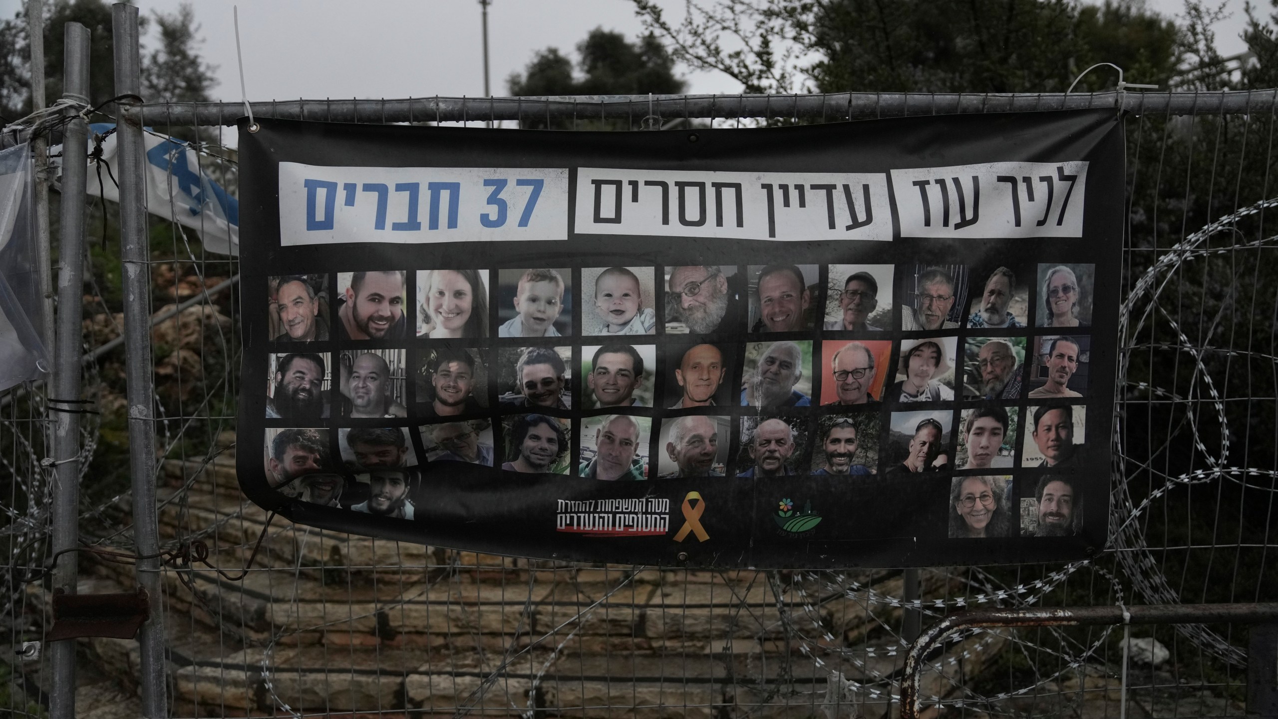 A poster shows portraits of Bibas family, top row from second left: Yarden, Shiri, and their sons Ariel and Kfir, who were kidnapped to Gaza on Oct. 7, 2023, in Jerusalem, Friday, Feb. 21, 2025. Letters on top read, "37 members of Kibbutz Nir Oz are still missing". (AP Photo/Mahmoud Illean)