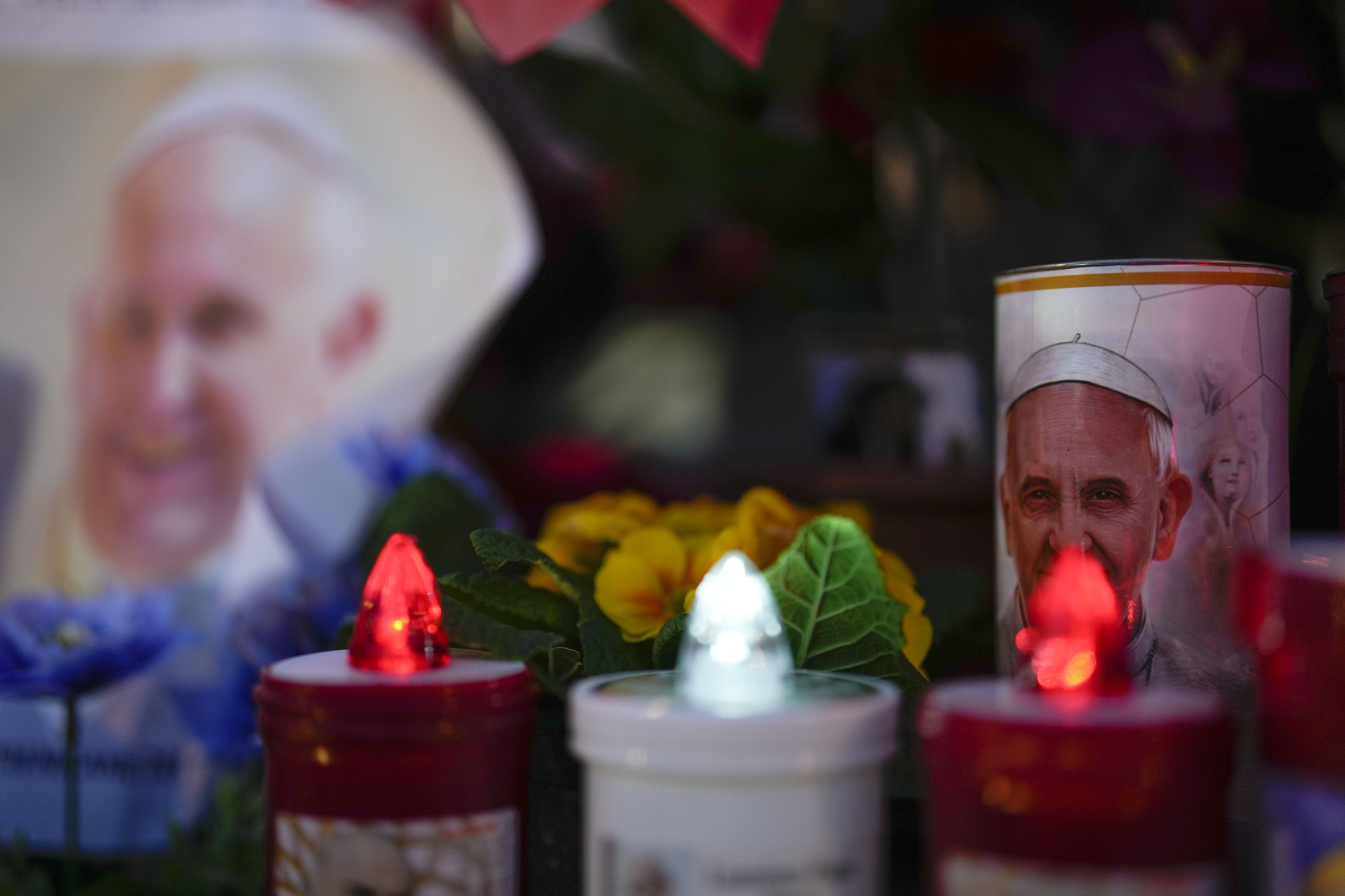 Candles are seen near pictures of Pope Francis outside the Agostino Gemelli Polyclinic in Rome, Sunday, Feb. 23, 2025, where the Pontiff is hospitalized since Feb. 14. (AP Photo/Gregorio Borgia)