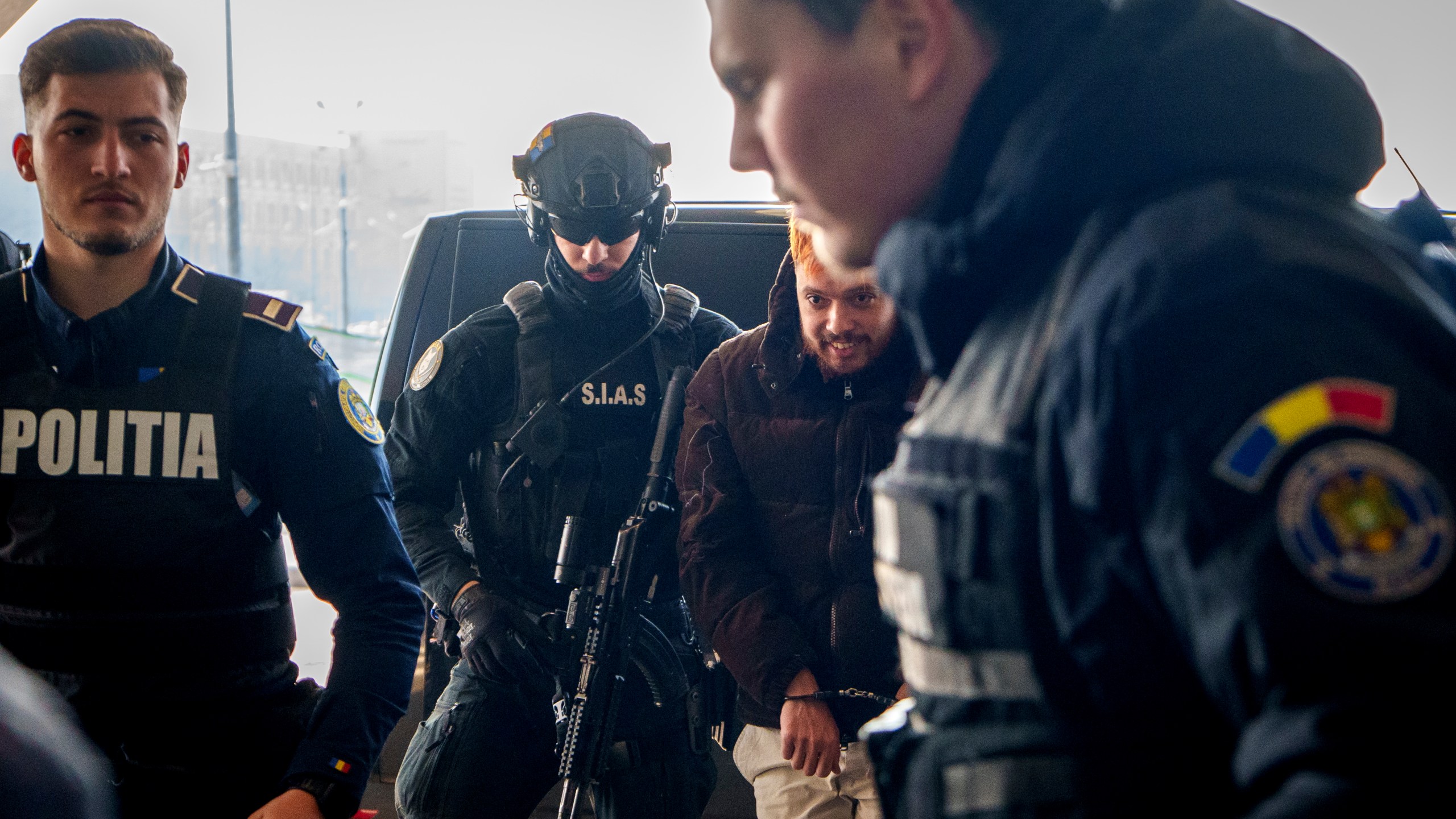 Mohamed Amra, nicknamed ''The Fly", is escorted by armed police officers at the Henri Coanda international airport in Otopeni, Romania, Tuesday, Feb. 25, 2025, before being extradited to France. (AP Photo/Vadim Ghirda)