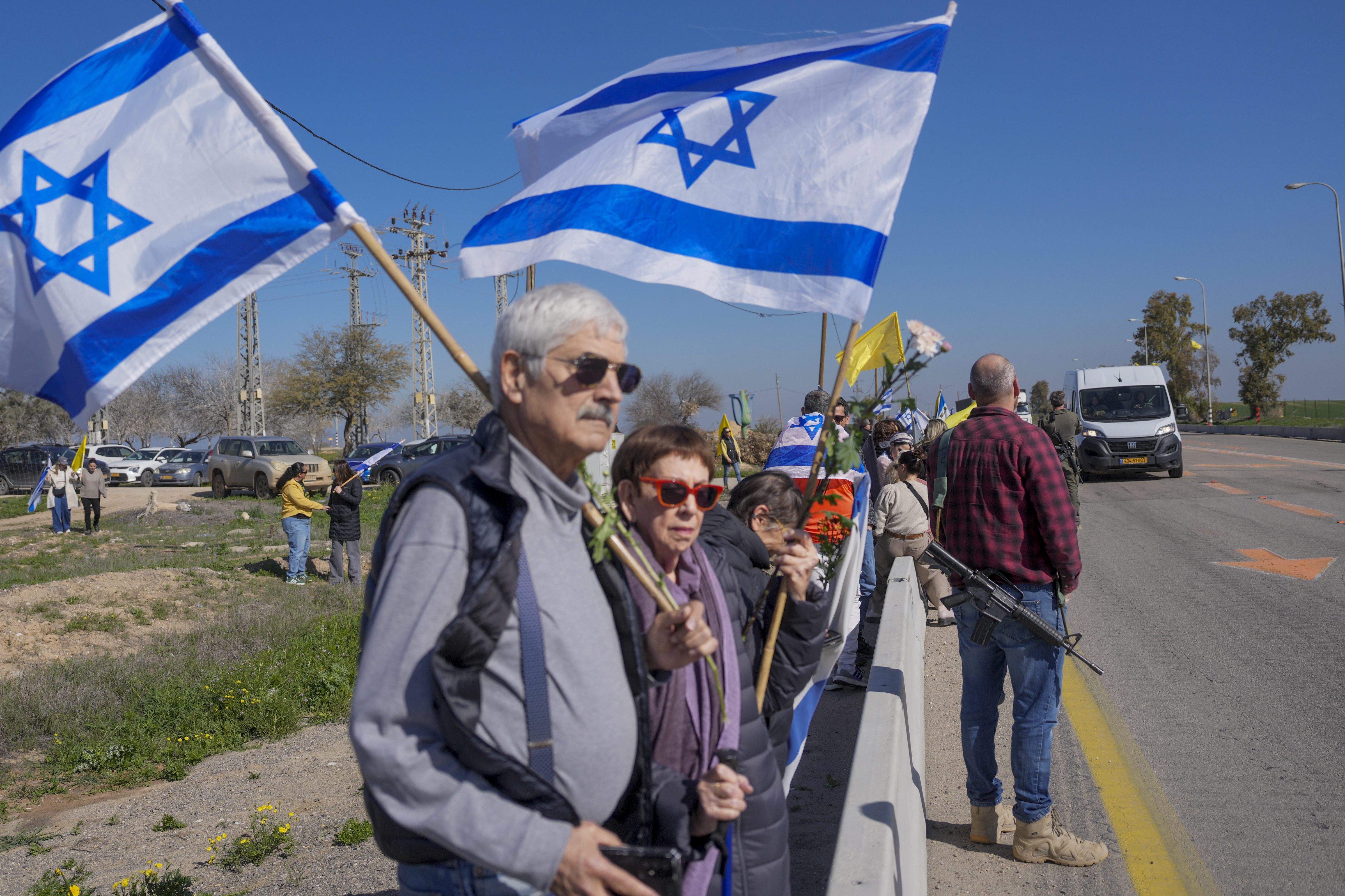 Israelis are waiting on the side of a road where the funeral convoy carrying the coffins of slain hostages Shiri Bibas and her two children, Ariel and Kfir, will pass by near Kibbutz Nir Oz, Israel, Wednesday, Feb. 26, 2025. The mother and her two children were abducted by Hamas on Oct. 7, 2023, and their remains were returned from Gaza to Israel last week as part of a ceasefire agreement with Hamas. (AP Photo/Ohad Zwigenberg)