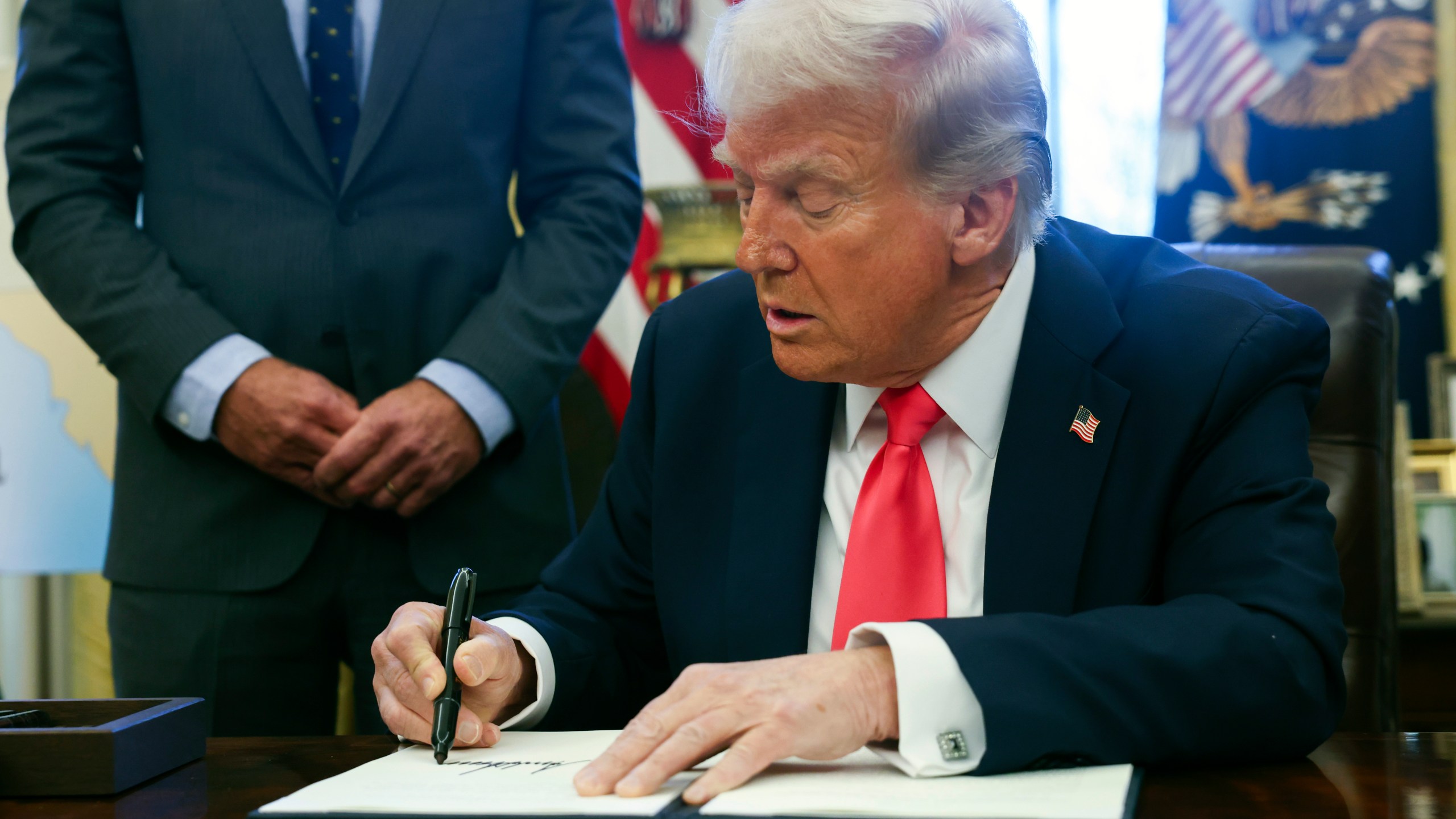 President Donald Trump signs an executive order in the Oval Office at the White House in Washington, Tuesday, Feb. 25, 2025. (Pool via AP)