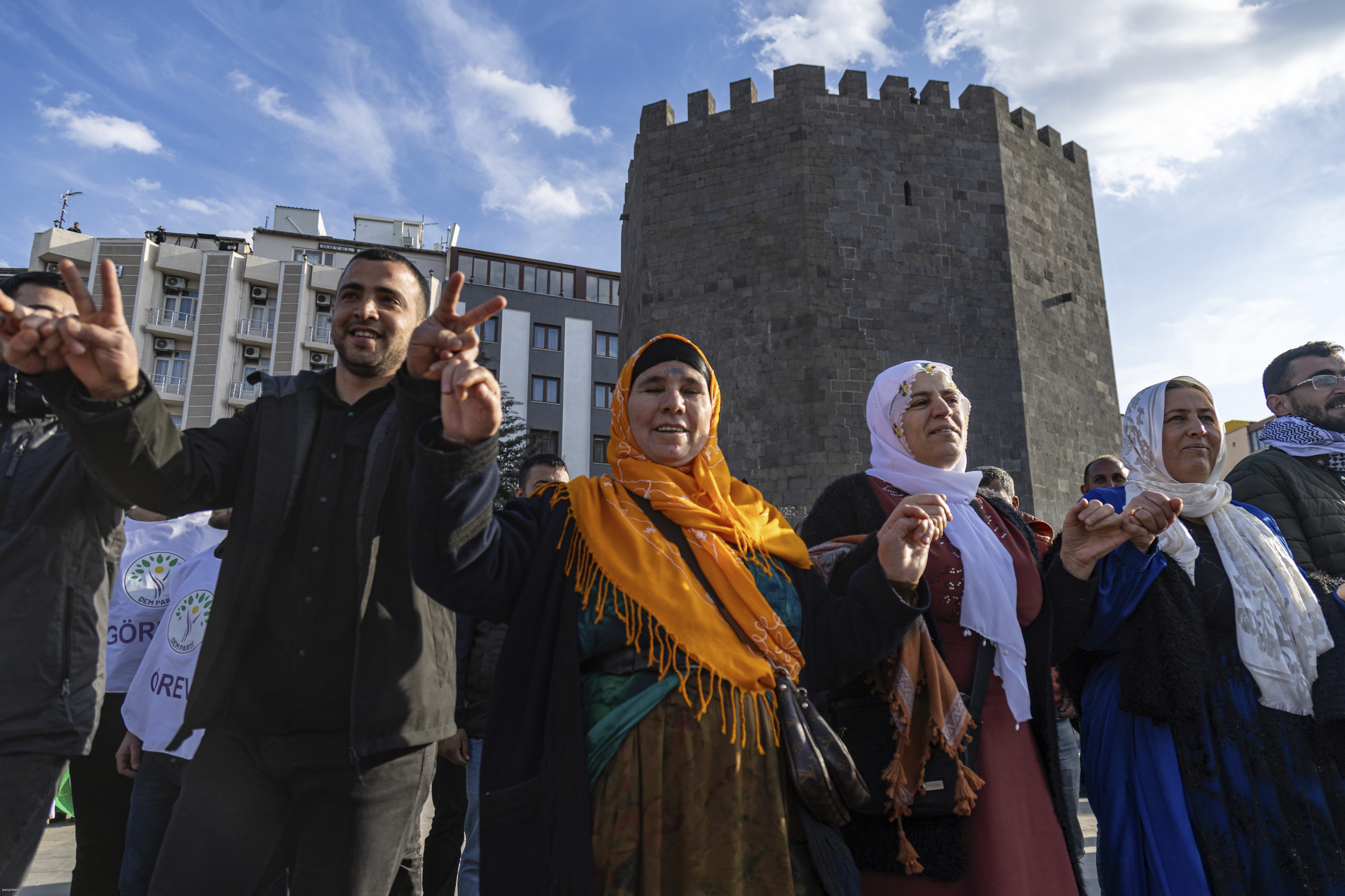 Kurdish people dance as they gather to watch live on a tv screen a Pro-Kurdish Peoples' Equality and Democracy Party, or DEM, delegation members releasing an statement from the jailed leader of the rebel Kurdistan Workers' Party, or PKK, Abdullah Ocalan, in Diyarbakir, Turkey, Thursday, Feb. 27, 2025. (AP Photo/Metin Yoksu)