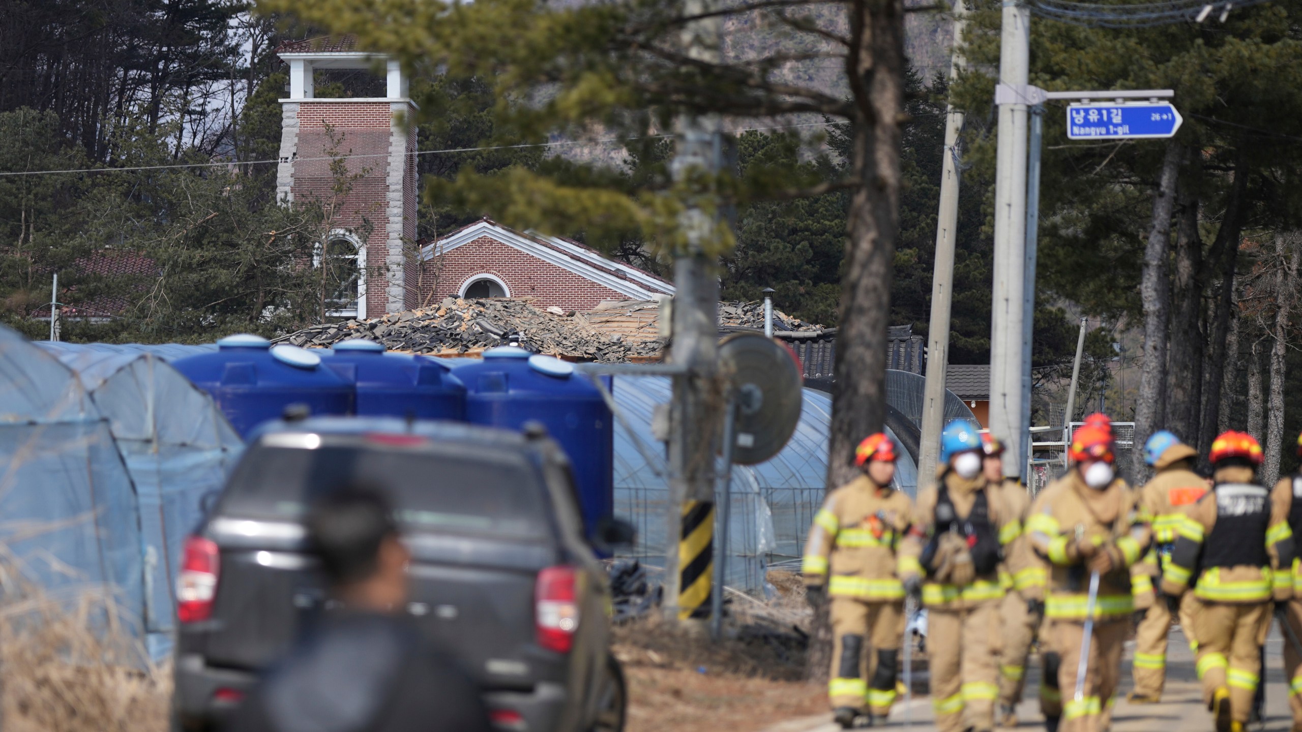 Firefighters walk near the site of an accidental bombing in Pocheon, South Korea, Thursday, March 6, 2025. (AP Photo/Lee Jin-man)