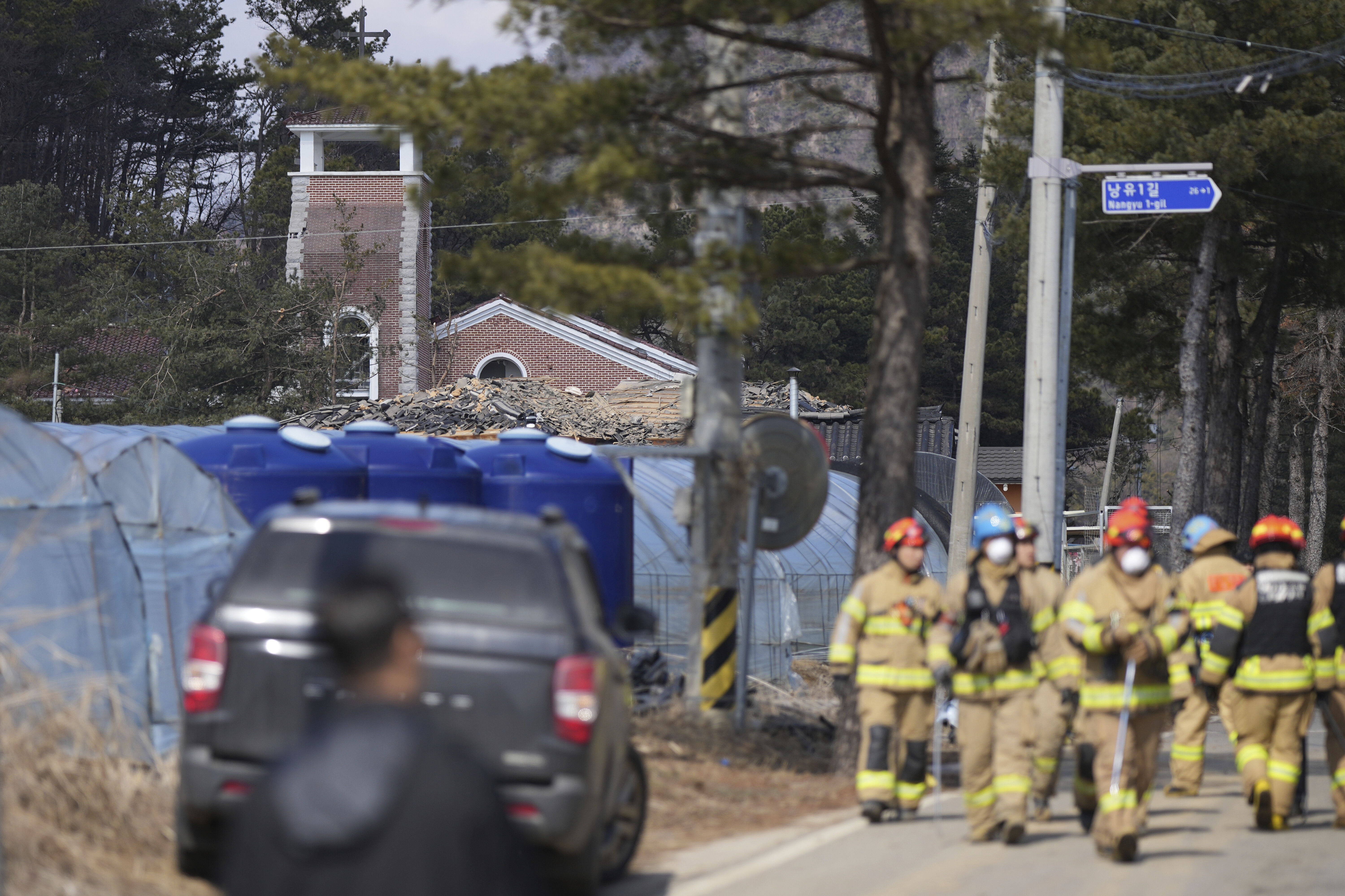 Firefighters walk near the site of an accidental bombing in Pocheon, South Korea, Thursday, March 6, 2025. (AP Photo/Lee Jin-man)