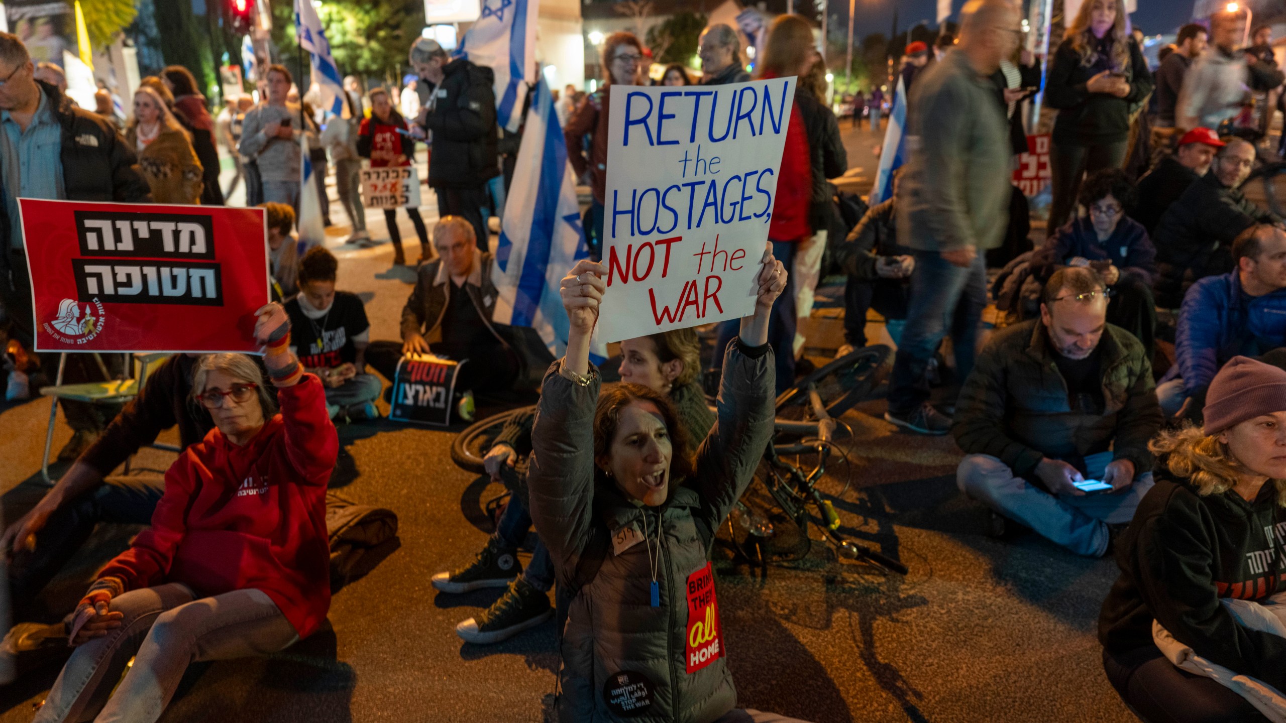 People block the entrance to Israel's defense ministry headquarters during a protest in Tel Aviv, Israel, Saturday, March 8, 2025, demanding the immediate release of hostages held by Hamas in the Gaza Strip. (AP Photo/Ariel Schalit)