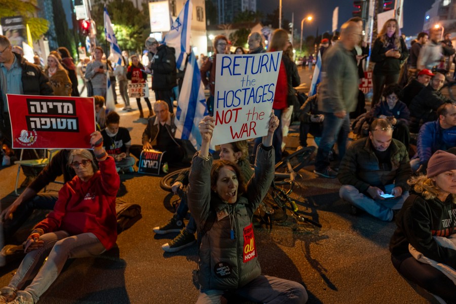 People block the entrance to Israel's defense ministry headquarters during a protest in Tel Aviv, Israel, Saturday, March 8, 2025, demanding the immediate release of hostages held by Hamas in the Gaza Strip. (AP Photo/Ariel Schalit)