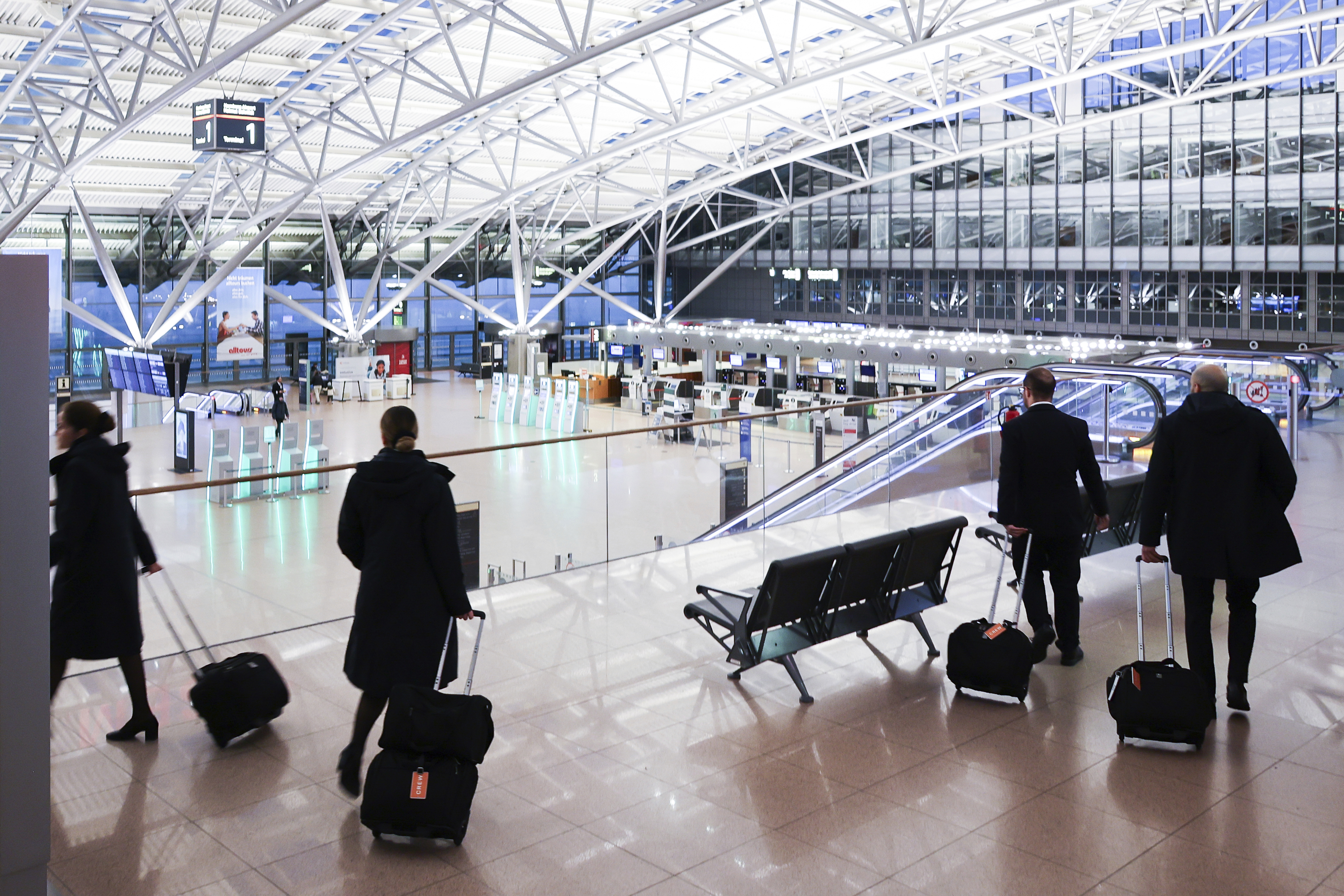 Crew members of an international airline walk through the almost deserted Terminal 1 at Hamburg Airport, Germany Monday, March 10, 2025. (Christian Charisius/dpa via AP)